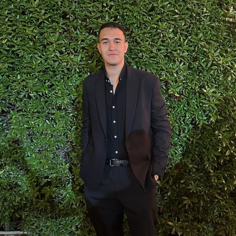 Professional headshot of a developer in a casual setting, smiling with a modern office background